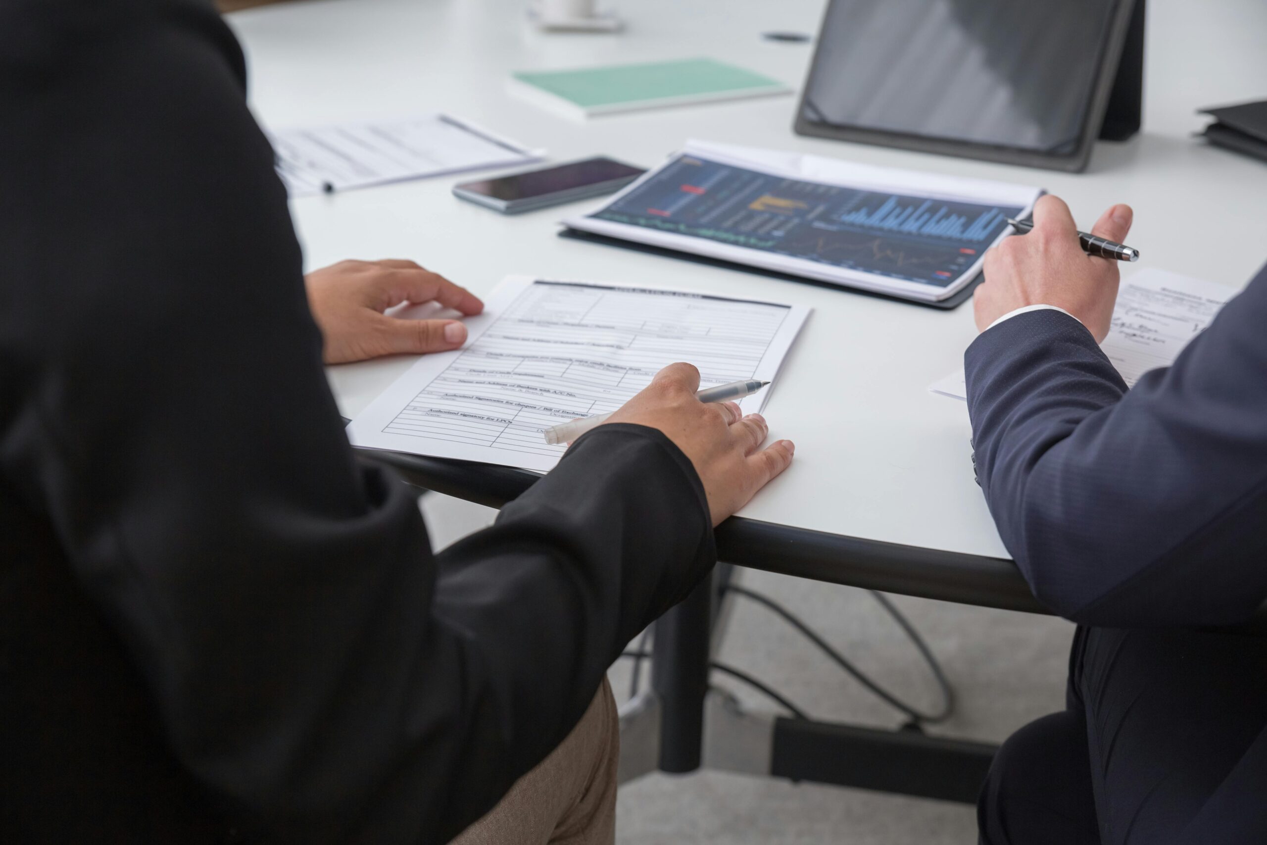 Close-up of professionals reviewing documents in an office setting, focused on analytics.